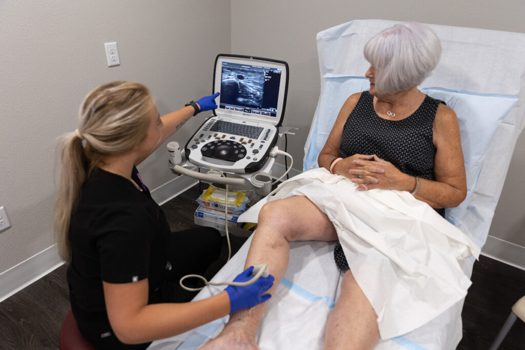 Mature woman laying on an exam bed getting a vein screening from a provider for Varicose Vein Treatment in North Port