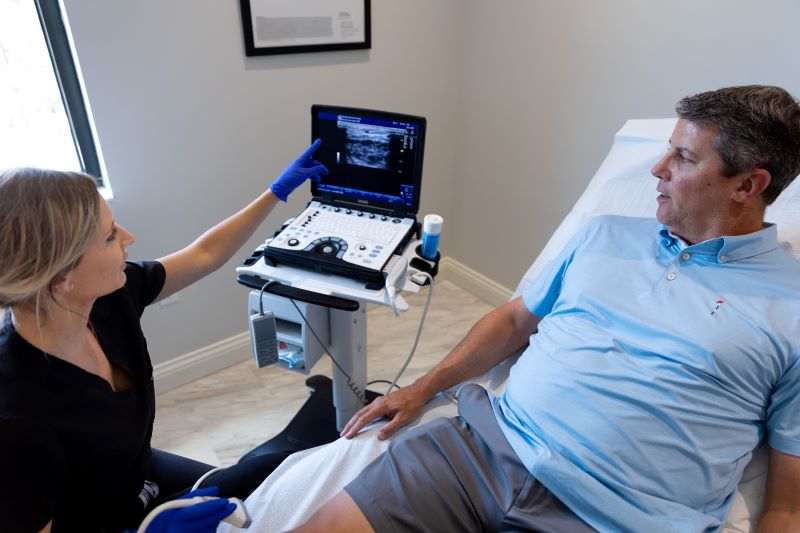 Mature man in blue shirt getting a vein screening with a young provider at a Vein Clinic Near Me in Wellen Park